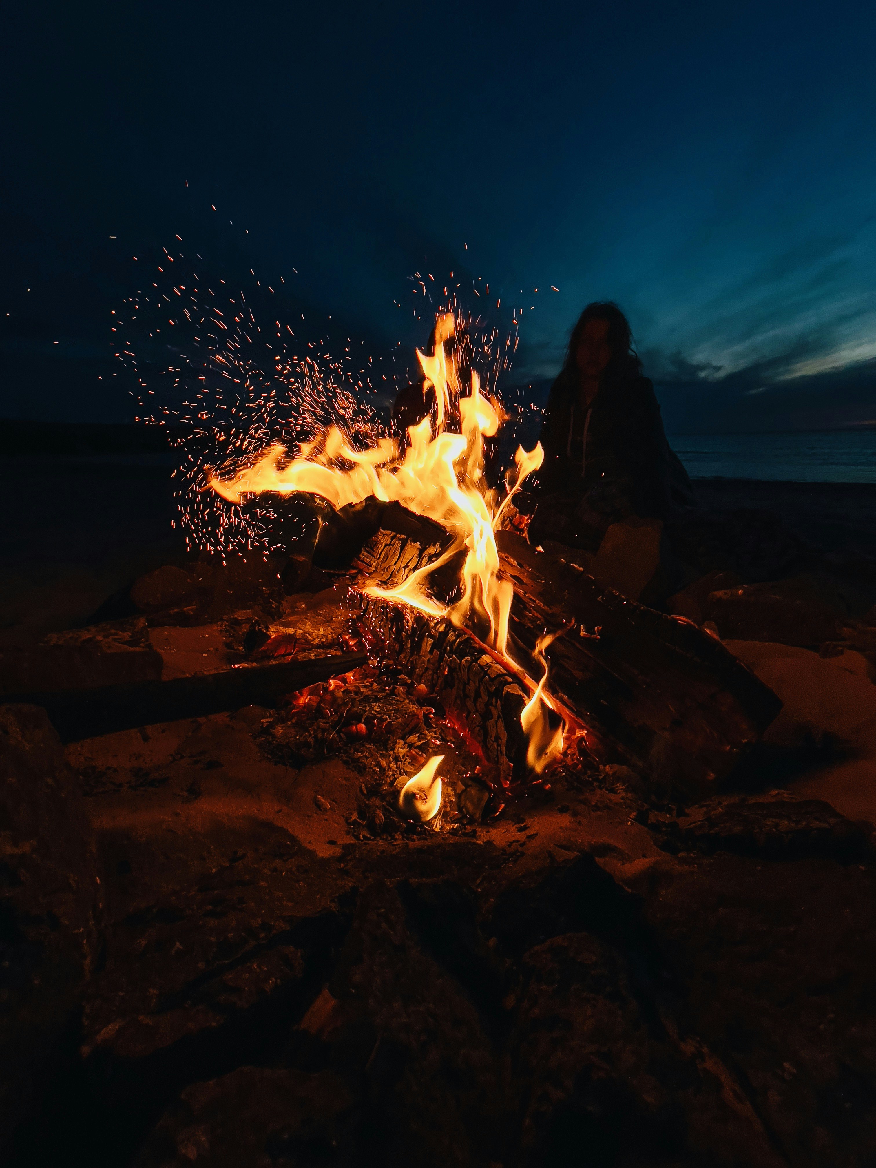 man in black jacket standing near bonfire during night time